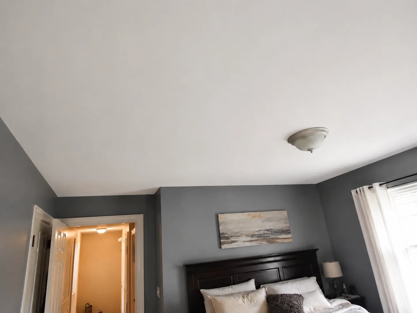 Bedroom ceiling after water-damage restoration and fresh white paint