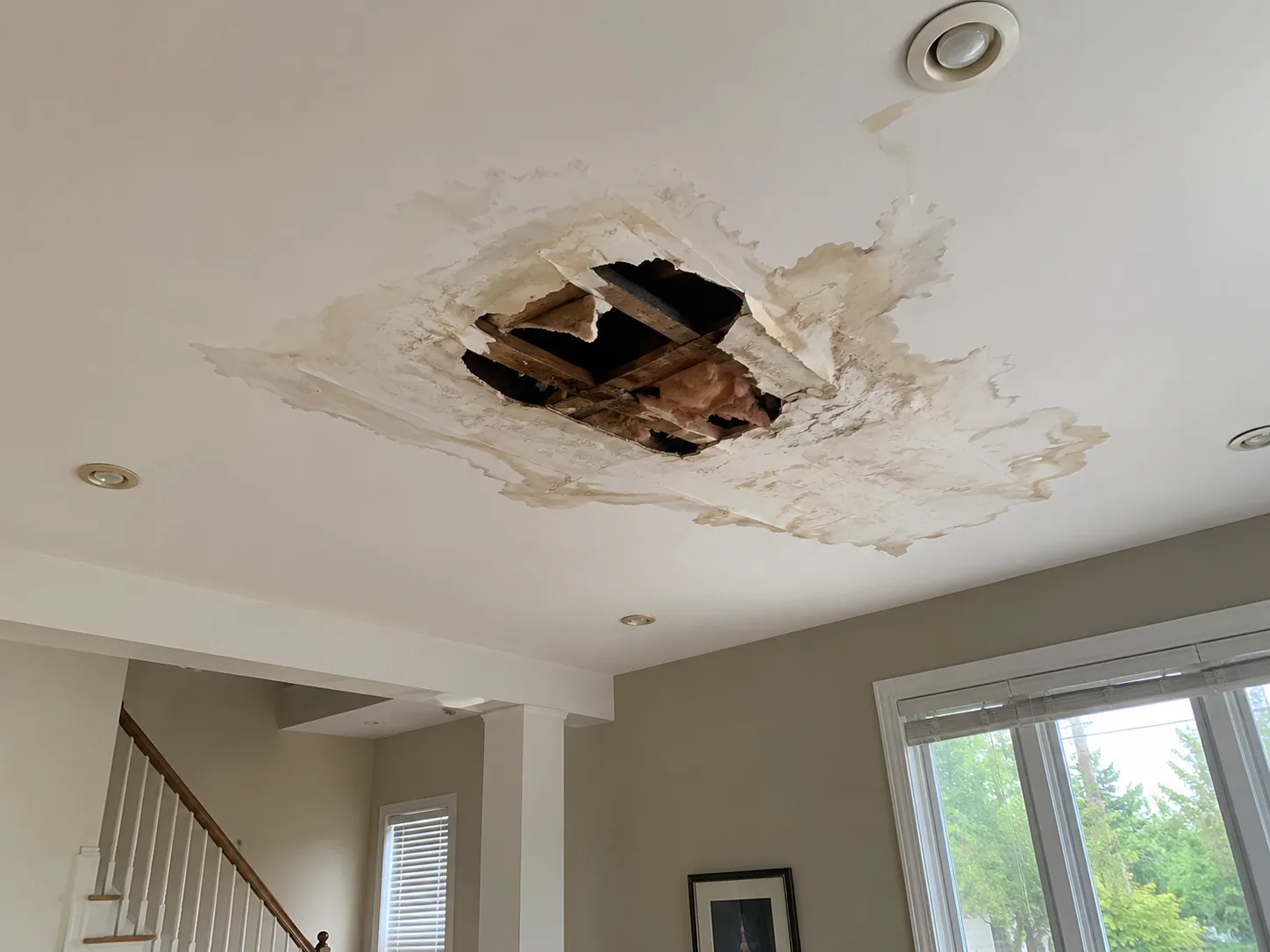 Large water-damaged ceiling hole exposing framing before drywall restoration